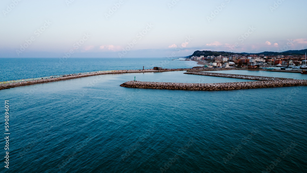 aerial view from the drone of the port of Pesaro with the rocks and people watching the sunset