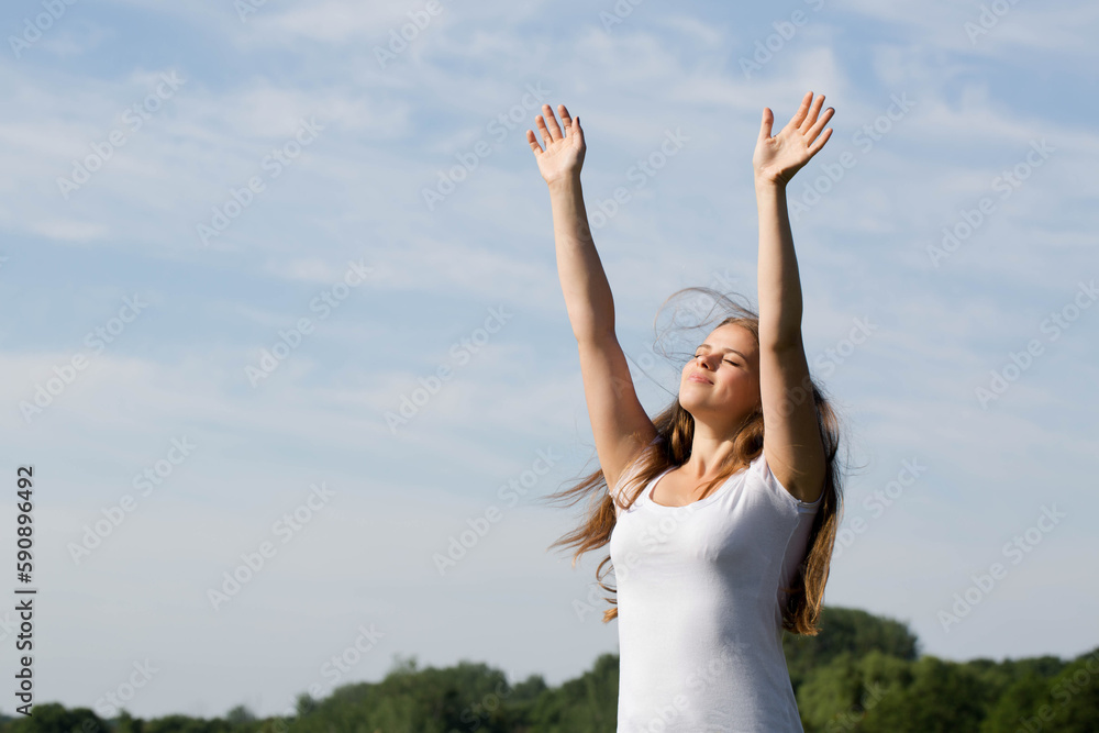 woman standing with arms raised, saluting the sun outdoors woman standing with arms raised, saluting the sun outdoors