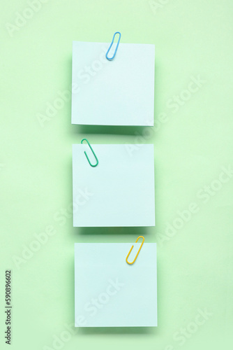 Sticky notes with paper clips on green background