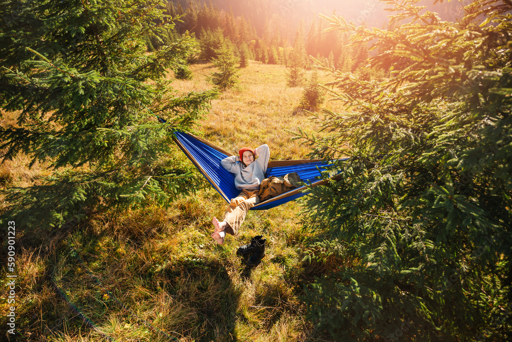Φωτογραφία Teenage child lies asleep in tourist hammock in the midst of beautiful mountain nature