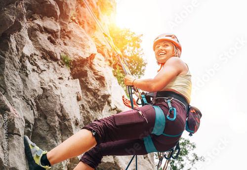 Smiling athletic woman in protective helmet and shoes climbing cliff rock wall using top rope and harness in Paklenica National park site in Croatia. Active extreme sports time spending concept photo