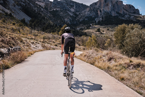 Man cyclist on a gravel bike riding on the road in the hills with a view of the mountains.Man cyclist wearing cycling kit and helmet