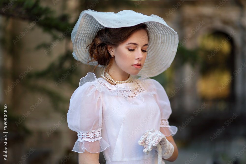 Φωτογραφία Young woman in white edwardian style dress and white big hat standing in old abandoned castle