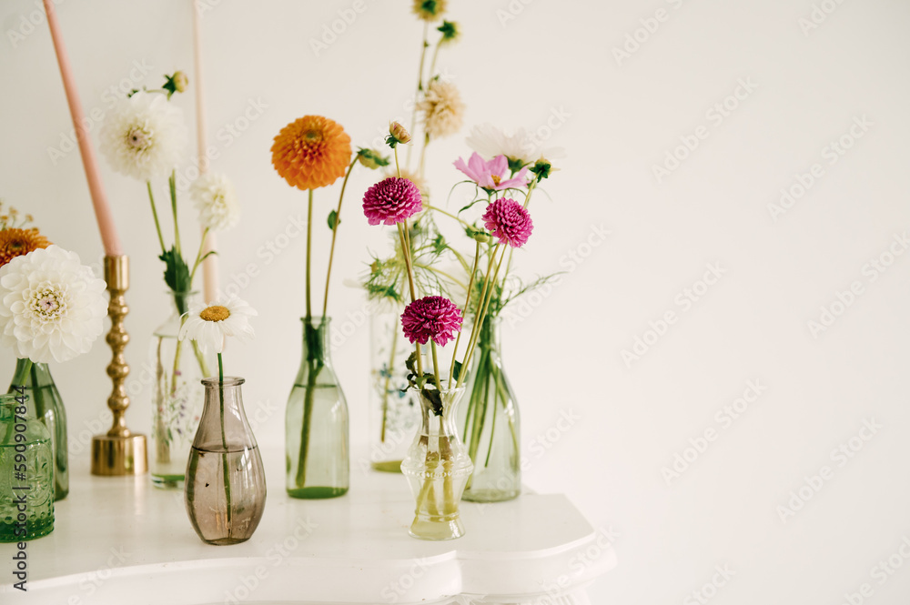 Beautiful flowers in glass vases decorate the fireplace at home