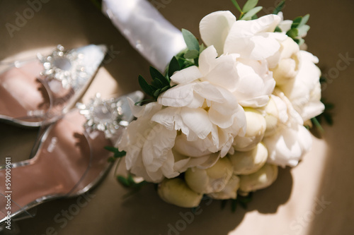 Beautiful white bridal bouquet of peonies and shoes in the sun