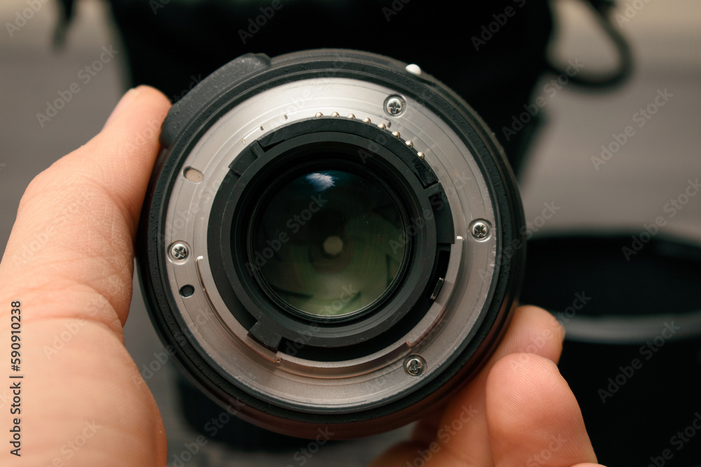 person holding camera lens and rear bayonet view of lens