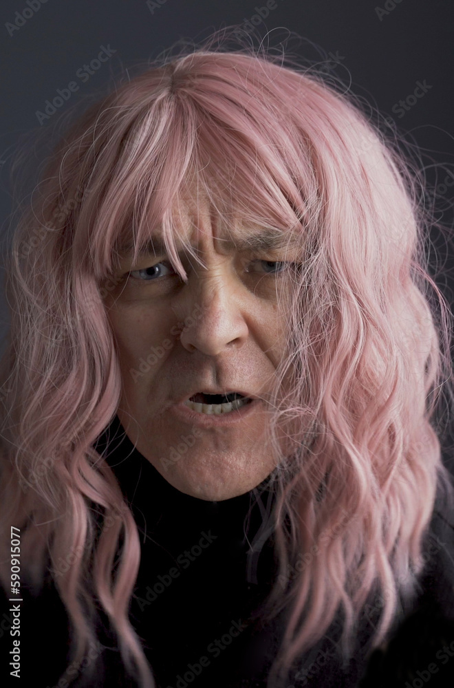 Portrait of an angry middle-aged man in a pink wig. Portrait of an angry middle-aged man in a pink wig.