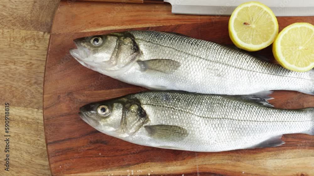 poisson bar entier, en gros plan, sur une planche à découper poisson bar entier, en gros plan, sur une planche à découper