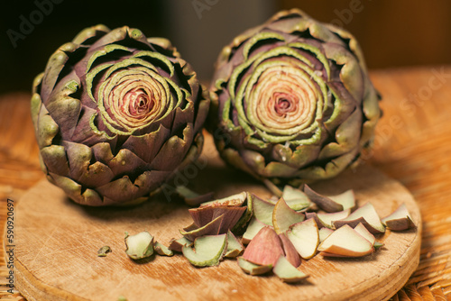 Purple artichokes on a wooden background. Artichokes with the top cut off. Preparation for cooking. Vegan healthy food.