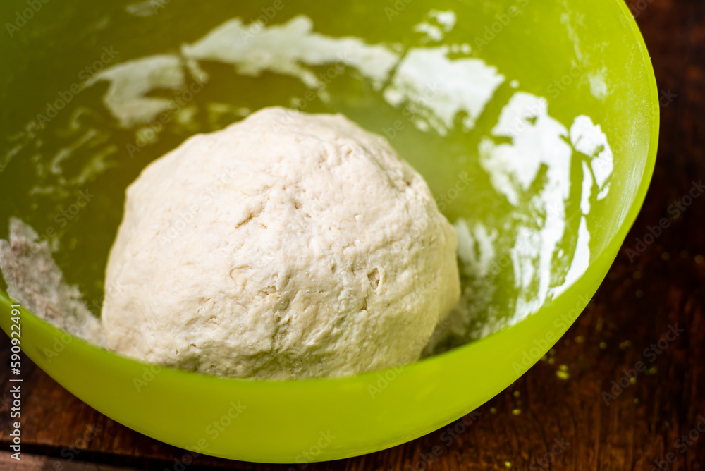 Dough ball in plastic bowl. Preparation of yeast dough for making bread, pizza bases.