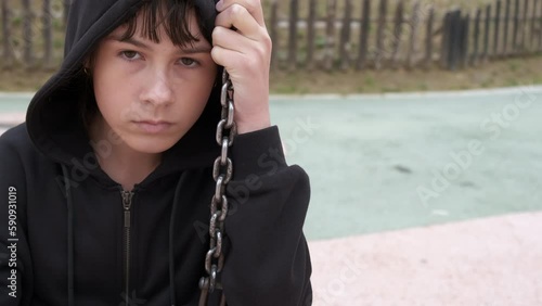 Teen without friend on playground. A view of upset young girl swinging and pass her time on playground without friends.