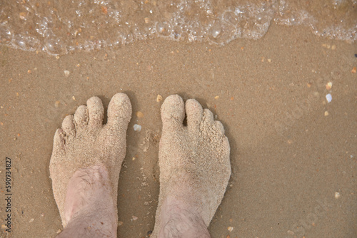 Feet are on the sand right on the beach, sea summer vacation.