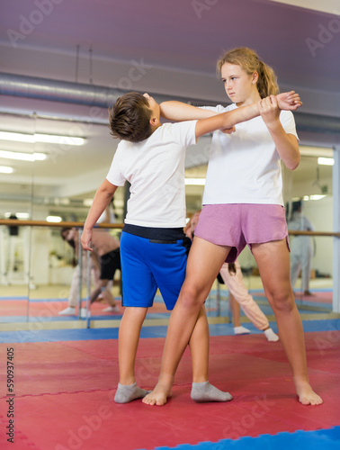 Preteen children working in pair mastering new self-defense moves at gym