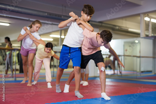 Two boys learn to do a painful hand grip in a self-defense lesson