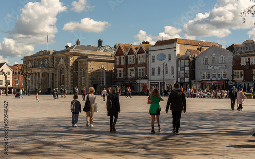 Salisbury, Wiltshire, England, UK. 2023. People walk on Market Place in the city centre surrounded with historic buildings, The Guildhall, shops and offices.
