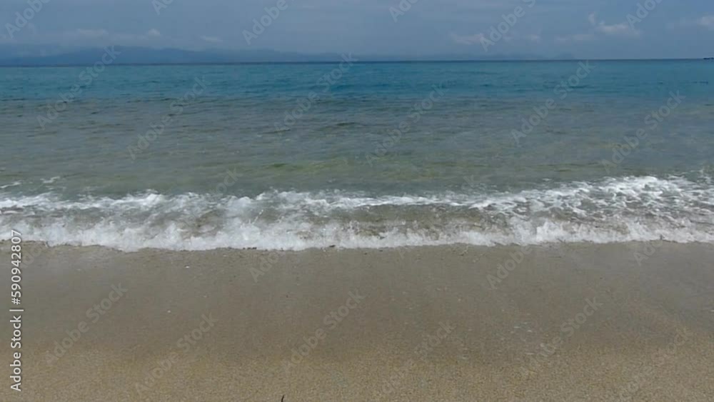 Gentle waves lapping onto a sandy beach, captured in slow motion to emphasize the calming and tranquil nature of the scene.