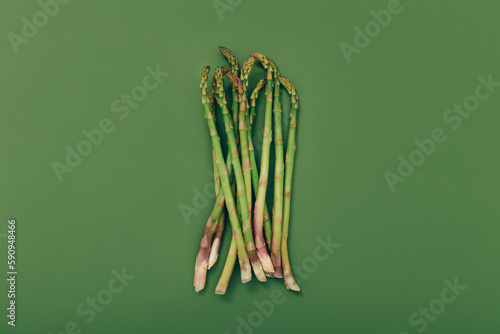 Food background. Fresh green asparagus on green background, top view.