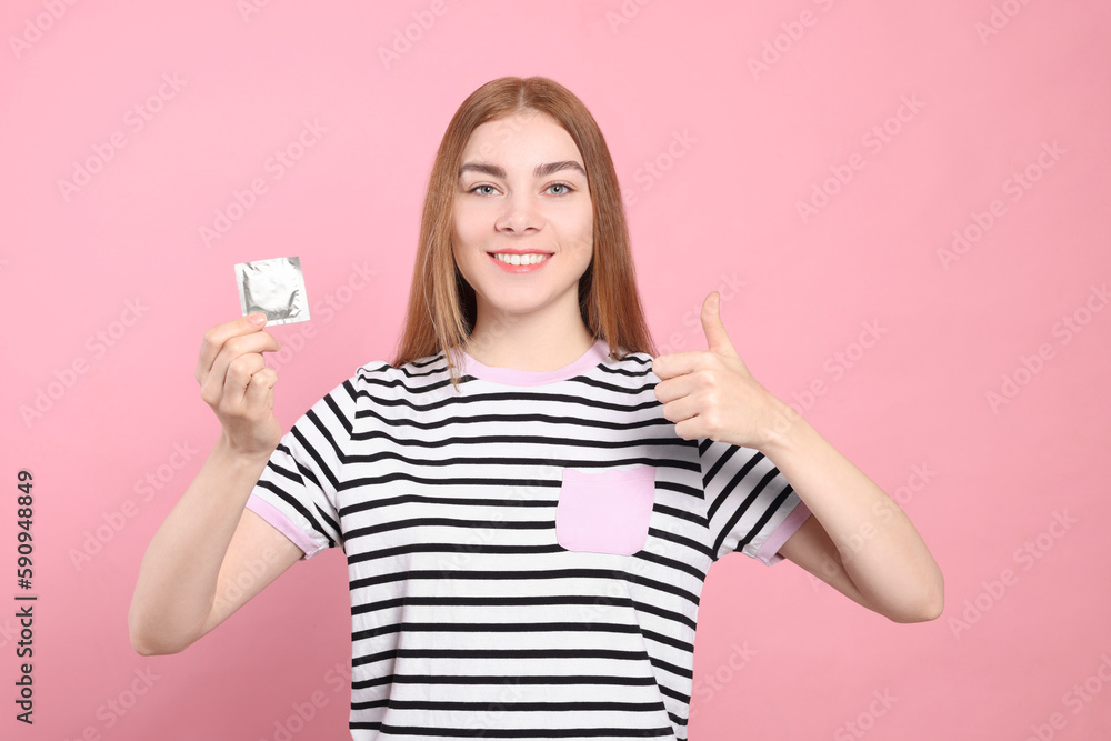 Woman with condom showing thumb up on pink background. Safe sex Woman with condom showing thumb up on pink background. Safe sex