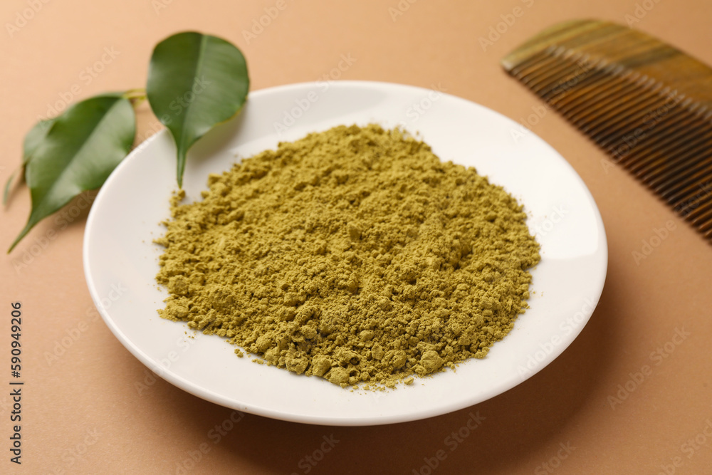 Henna powder, comb and green leaves on coral background. Natural hair coloring Henna powder, comb and green leaves on coral background. Natural hair coloring