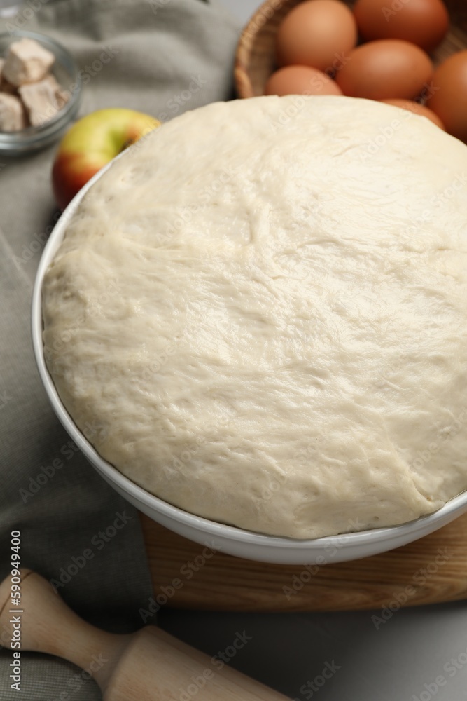 Fresh yeast dough, rolling pin and ingredients on grey table, closeup. Making cake Fresh yeast dough, rolling pin and ingredients on grey table, closeup. Making cake