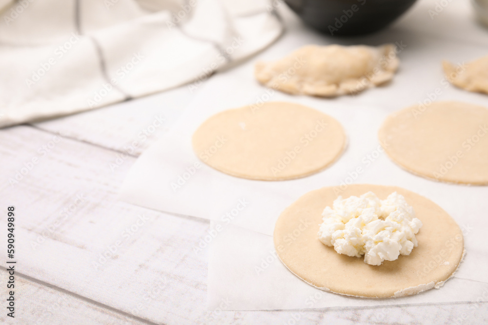 Process of making dumplings (varenyky) with cottage cheese. Raw dough and ingredients on white wooden table, closeup. Space for text