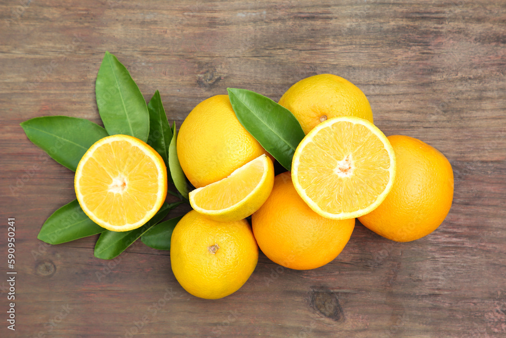 Many ripe oranges and green leaves on wooden table, flat lay Many ripe oranges and green leaves on wooden table, flat lay