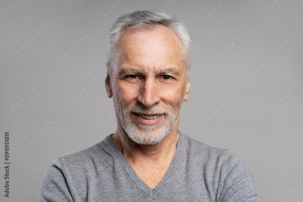 Closeup portrait of smiling senior man with beard and gray hair looking at camera isolated on gray background. Health care, dental concept Closeup portrait of smiling senior man with beard and gray hair looking at camera isolated on gray background. Health care, dental concept
