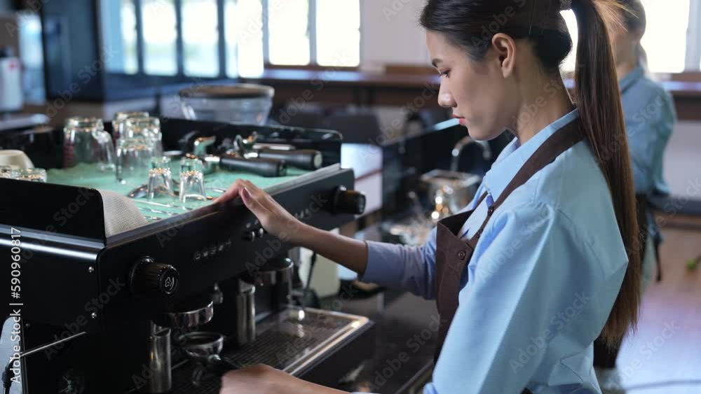 Asian female barista pouring freshly brewed coffee into a mug ready to serve to customers. Asian female barista pouring freshly brewed coffee into a mug ready to serve to customers.