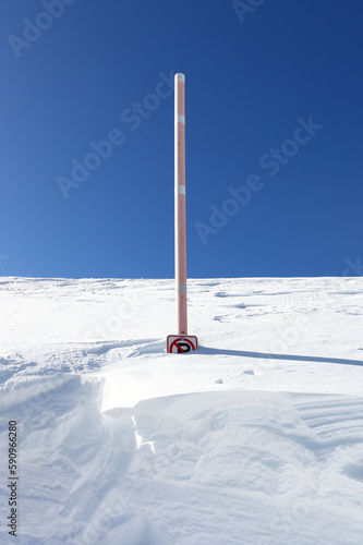 A no-parking sign covered by feet of snow against a clear blue sky