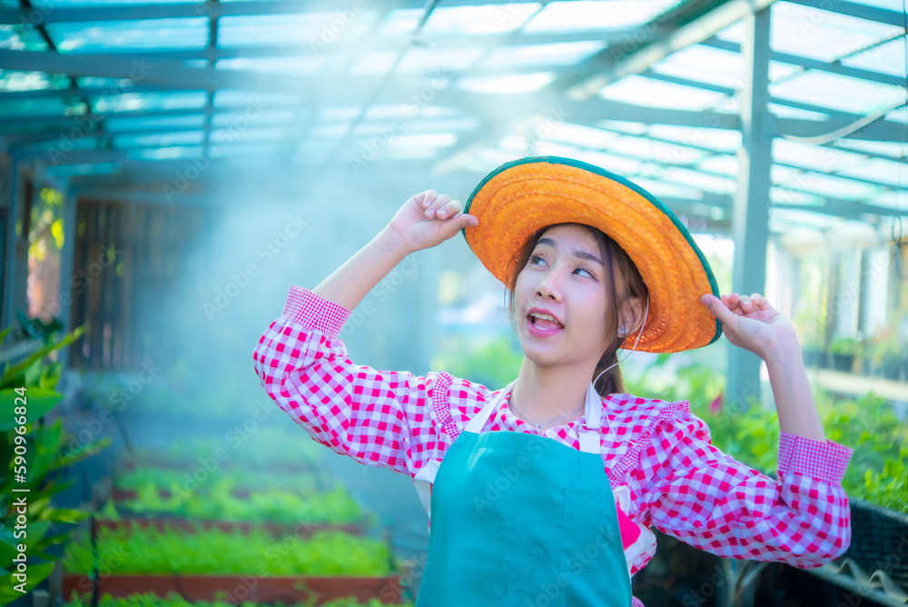 Beautiful asian farmer holding a hat and looking at the copy space In the organic vegetable garden with a smile, Smart farm.