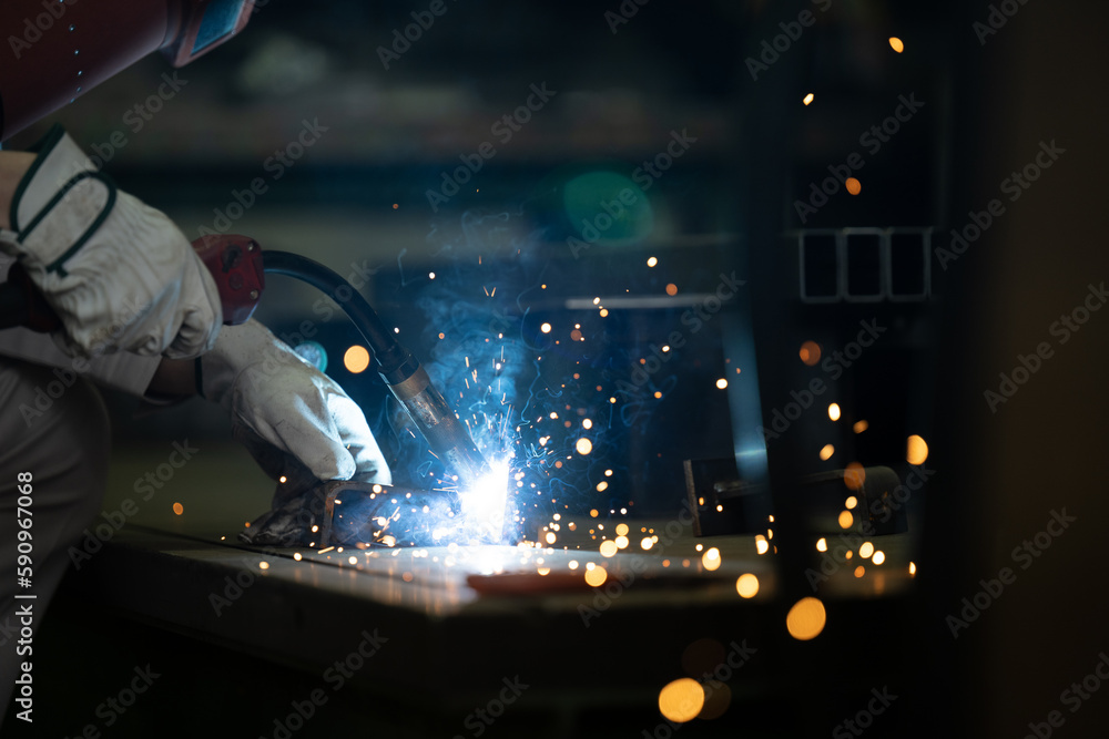 A worker's hand in a factory welding with sparks easy to use in design Up no-face - obrazy, fototapety, plakaty 
