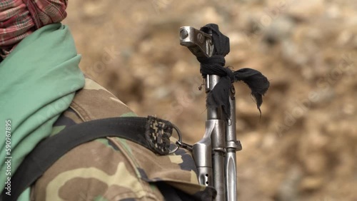 Close-up of weapon over shoulder of taliban man in turban and military jacket photo