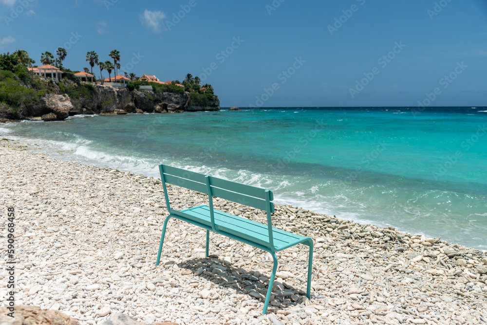 Blue chair on a beach with coral stones on the shore on the island of Curacao. Netherlands Antilles.