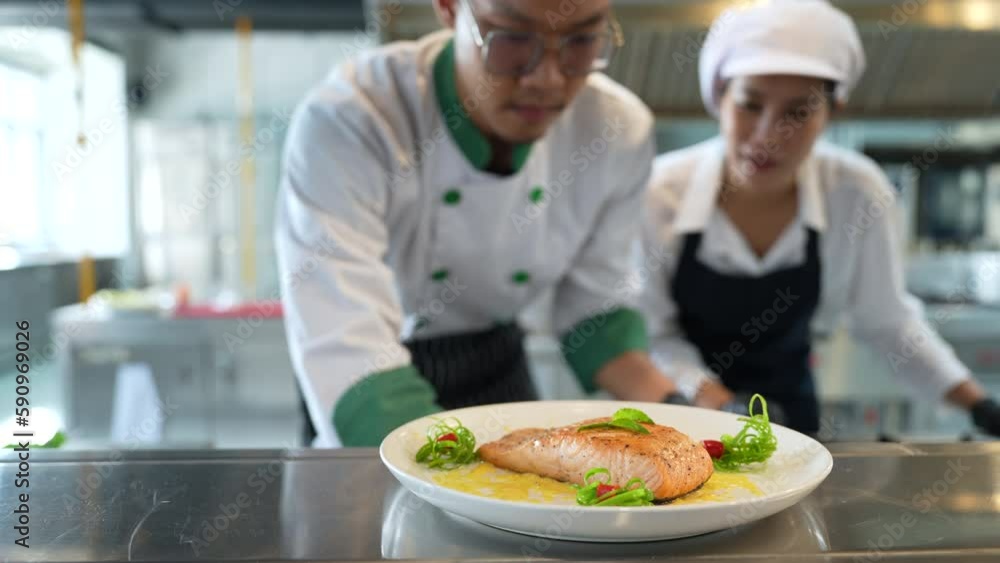 Asian male chef sprinkles salt and pepper seasoning on salmon steak. Asian male chef sprinkles salt and pepper seasoning on salmon steak.