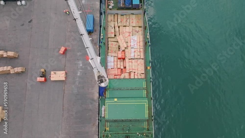 High angle view over cargo ship being unloaded by industrial crane at seaport photo