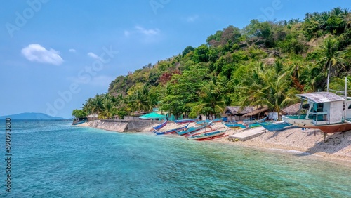 A picturesque fishing village with colorful wooden banca boats on the beach, located in San Antonio Barangay on Verde Island, Batangas Province, in the Philippines.