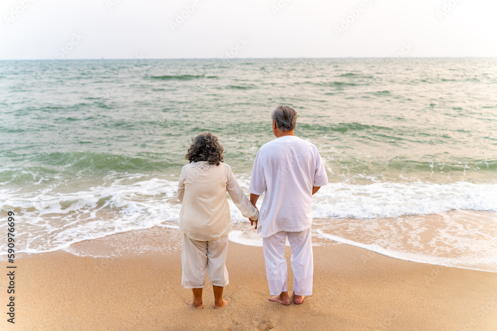 Happy Asian family senior couple with gray hair walking together at tropical beach at summer sunset. Retired elderly people enjoy romantic outdoor lifestyle travel nature ocean on holiday vacation. Happy Asian family senior couple with gray hair walking together at tropical beach at summer sunset. Retired elderly people enjoy romantic outdoor lifestyle travel nature ocean on holiday vacation.
