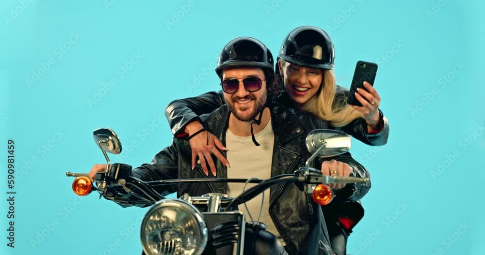 Selfie, travel and couple on motorcycle for adventure, road trip and holiday on blue background. Motorbike transport, studio and excited man and woman take picture for social media, post or memory Selfie, travel and couple on motorcycle for adventure, road trip and holiday on blue background. Motorbike transport, studio and excited man and woman take picture for social media, post or memory