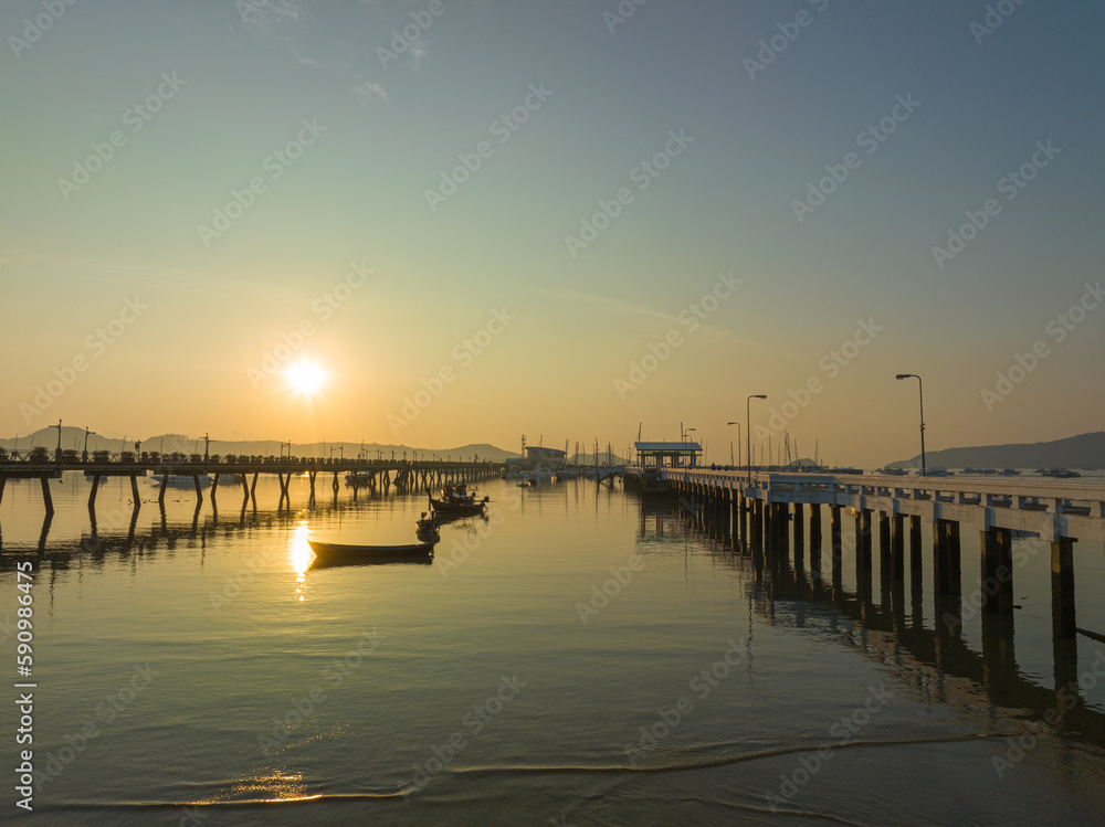 aerial view fishing boats on the beach at Chalong pier in sunrise..Sunrise with sweet yellow color light rays and other atmospheric effects..colorful reflection of sunrise in the sea background..d.