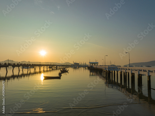 aerial view fishing boats on the beach at Chalong pier in sunrise..Sunrise with sweet yellow color light rays and other atmospheric effects..colorful reflection of sunrise in the sea background..d. © Narong Niemhom