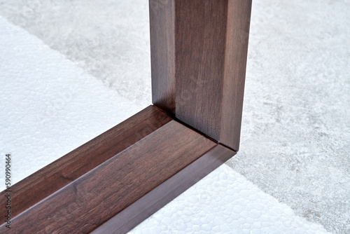 Wooden frame of bedside table made of solid walnut in workshop. Joinery angular joint of planks on dowels closeup