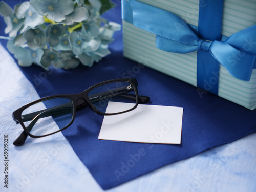 青いリボンのプレゼント、メガネとネクタイと時計と花とメッセージカード