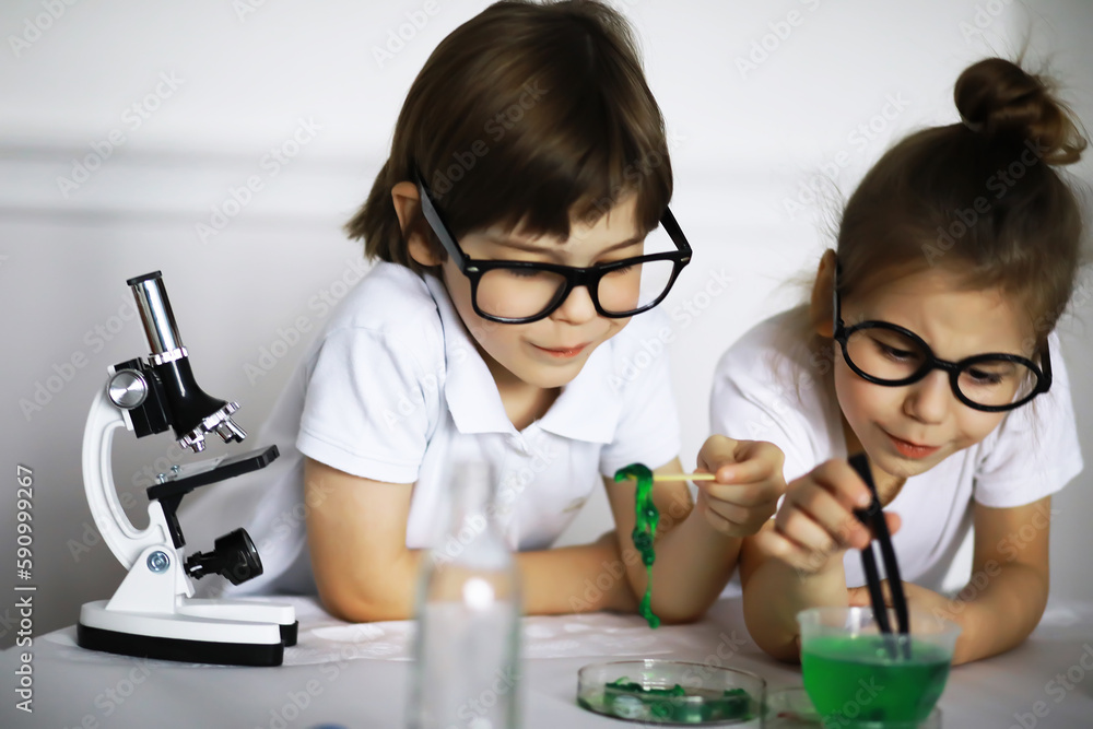 Two cute children at chemistry lesson making experiments on white background Two cute children at chemistry lesson making experiments on white background