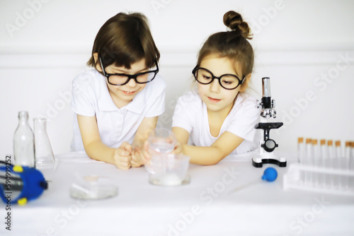 Two cute children at chemistry lesson making experiments on white background