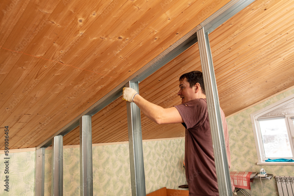 A man installs a metal profile for a wall in a room. A man installs a metal profile for a wall in a room.