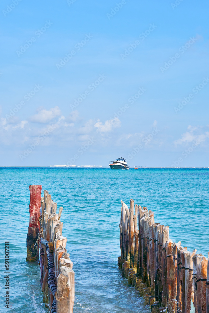 large yacht on the caribbean beaches of cancun Mexico. blue sky with lots of clouds and old wood in foreground out of focus. large yacht on the caribbean beaches of cancun Mexico. blue sky with lots of clouds and old wood in foreground out of focus.