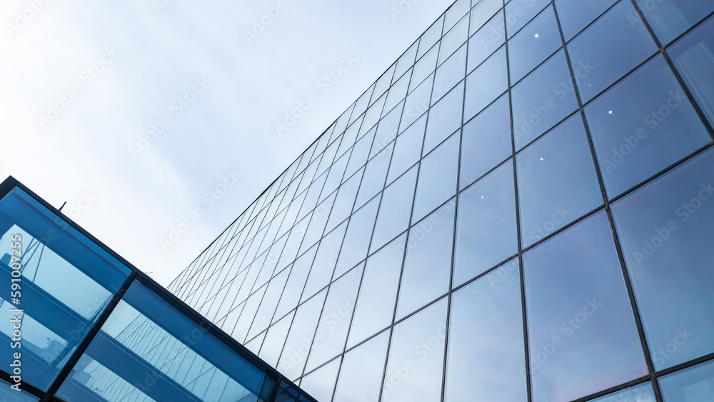 Obraz premium The blue sky is reflected in the windows of a modern office building. Architecture and exterior of contemporary houses