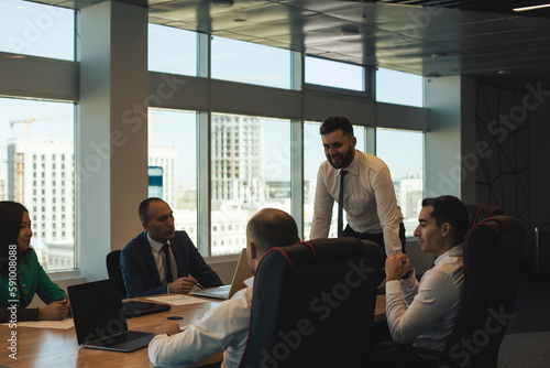 Silhouettes of people sitting at the table. Team of young business people working and communicating together in a modern office. Corporate team and manager in a meeting