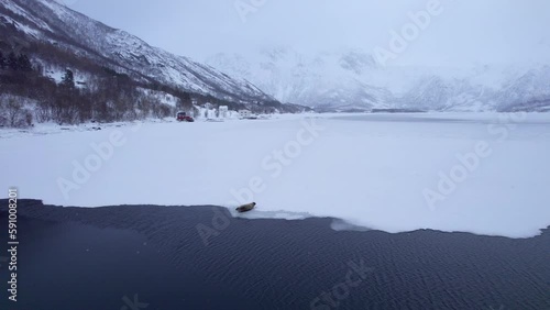 Dramatic dolly forward aerial view of a seal laying on the sea ice with snow capped mountains and valley in the background photo