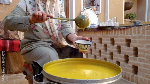 Wide view of a Persian Iranian woman serving sweet juicy dessert in Ramadan wear Muslim hijab in a local house with traditional architecture brick pattern in the backyard in Ardakan Yazd photo